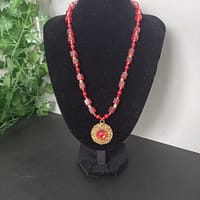 20250120_144601 Collier rouge avec pendentif soleil doré et cabochon rouge, perles de verre rouges et perles tibétaines dorées.