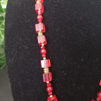20250120_144608 Collier rouge avec pendentif soleil doré et cabochon rouge, perles de verre rouges et perles tibétaines dorées.