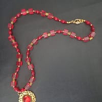 20250120_144652 Collier rouge avec pendentif soleil doré et cabochon rouge, perles de verre rouges et perles tibétaines dorées.