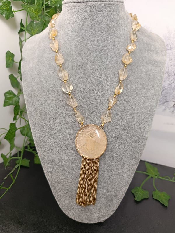 Collier raffiné en cristal de roche jaune, orné d’un pendentif rond doré avec pampilles.