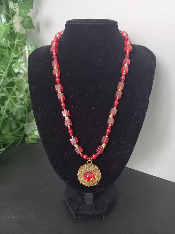 Collier rouge avec pendentif soleil doré et cabochon rouge, perles de verre rouges et perles tibétaines dorées.