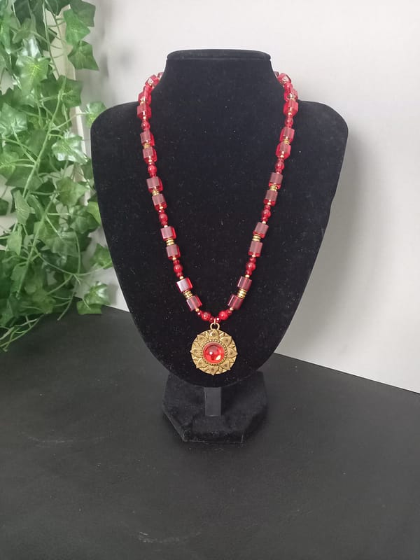 Collier rouge avec pendentif soleil doré et cabochon rouge, perles de verre rouges et perles tibétaines dorées.