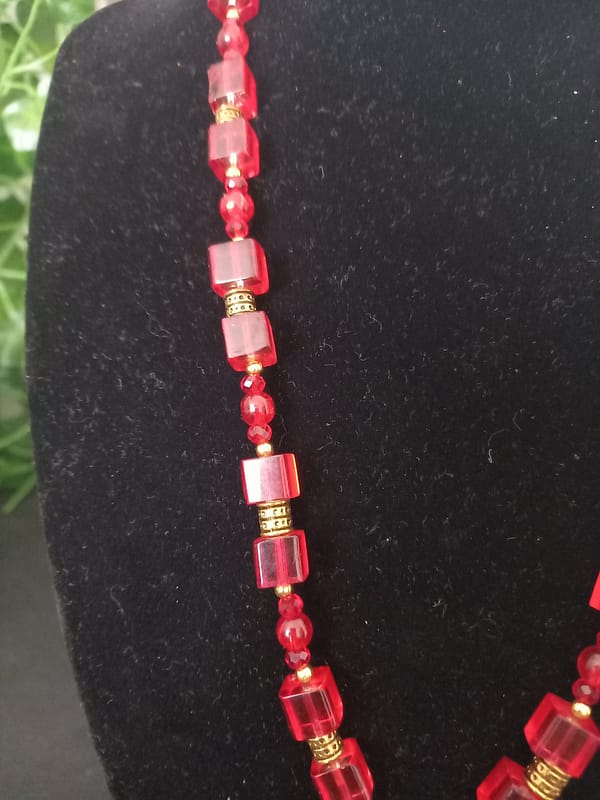 Collier rouge avec pendentif soleil doré et cabochon rouge, perles de verre rouges et perles tibétaines dorées.