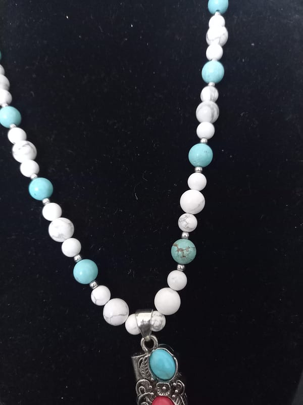 20250120_144929 Collier avec perles de howlite bleu et blanche, pendentif griffe décoré d’alliage argenté incrusté de pierres howlite bleu et rouge.