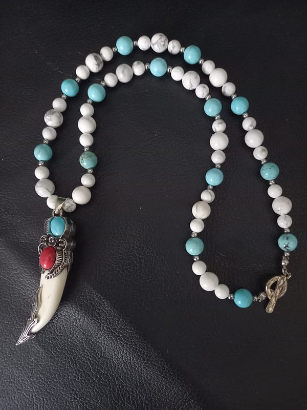 20250120_144955 Collier avec perles de howlite bleu et blanche, pendentif griffe décoré d’alliage argenté incrusté de pierres howlite bleu et rouge.