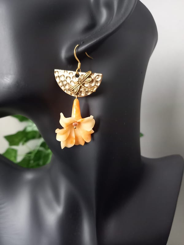 Boucles d’oreilles avec fleur de corail orange suspendue, demi-cercle doré martelé et libellule.