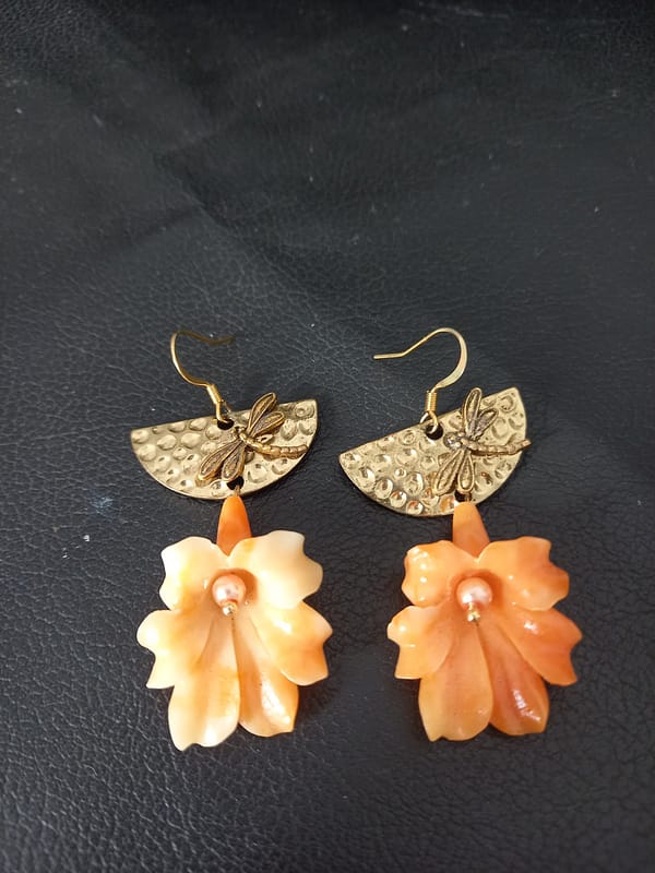 20250129_135037 Boucles d’oreilles avec fleur de corail orange suspendue, demi-cercle doré martelé et libellule.